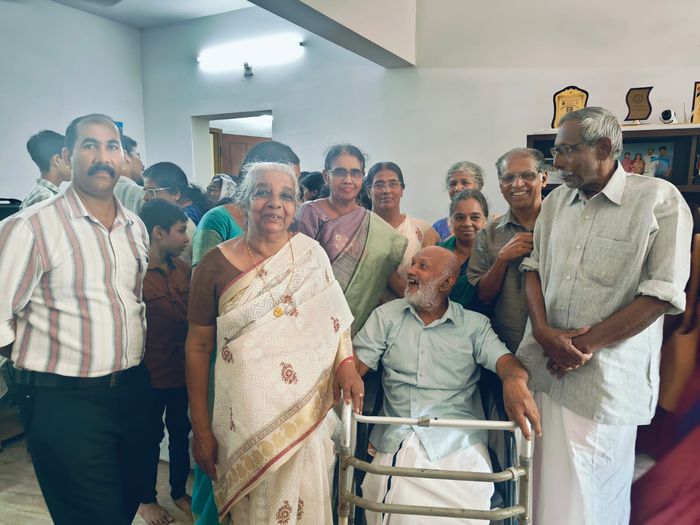 Mr. T.A. Pathrose Tholanikunnel laughing among family and friends gathered around him at home